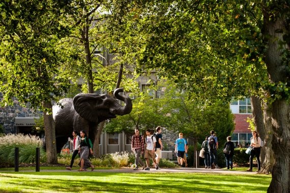 Jumbo statue and students walking around it on the campus of Tufts University.