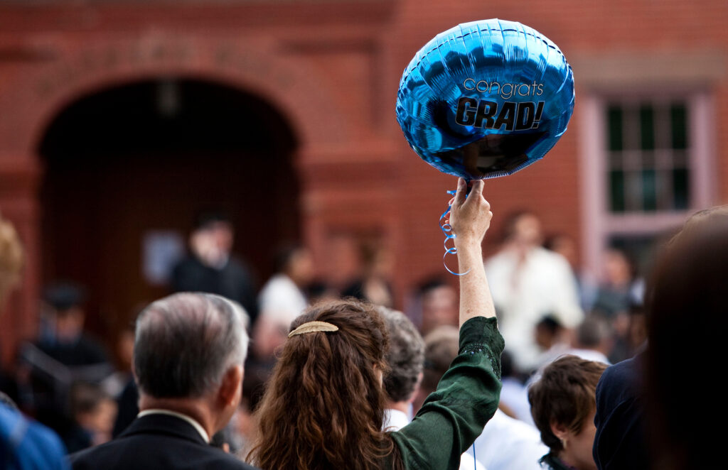 A woman holding a congrat grad balloon.