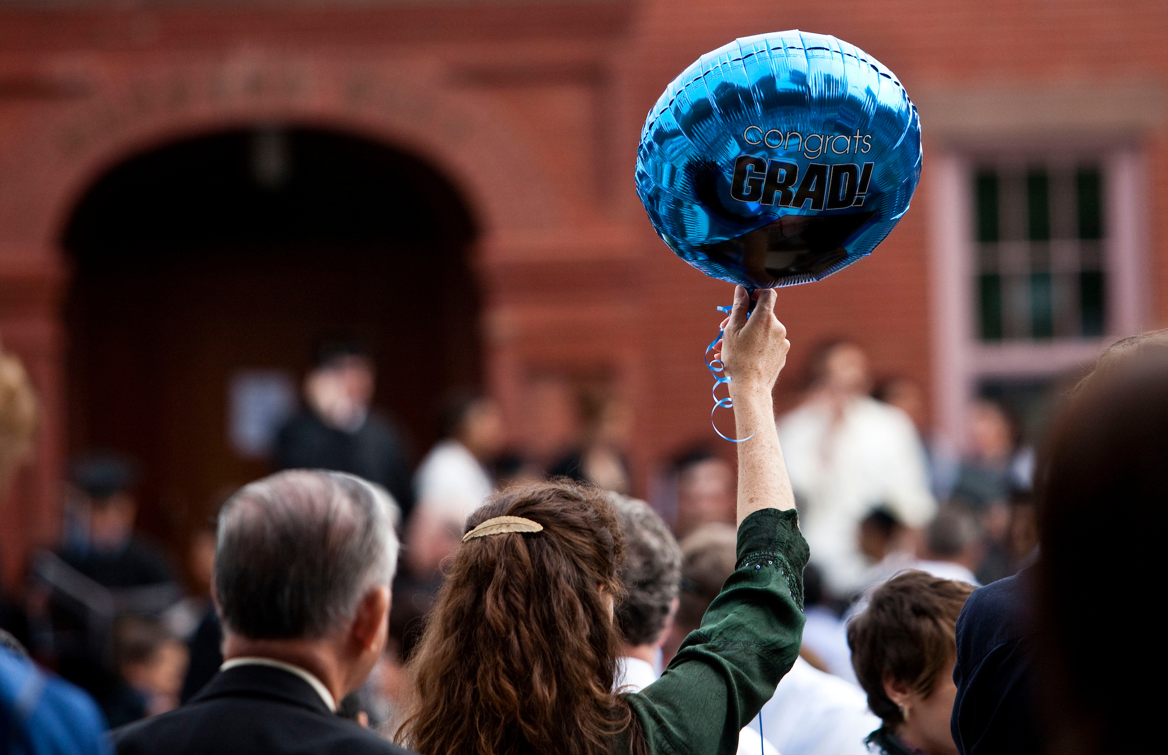 A woman holding a congrat grad balloon.