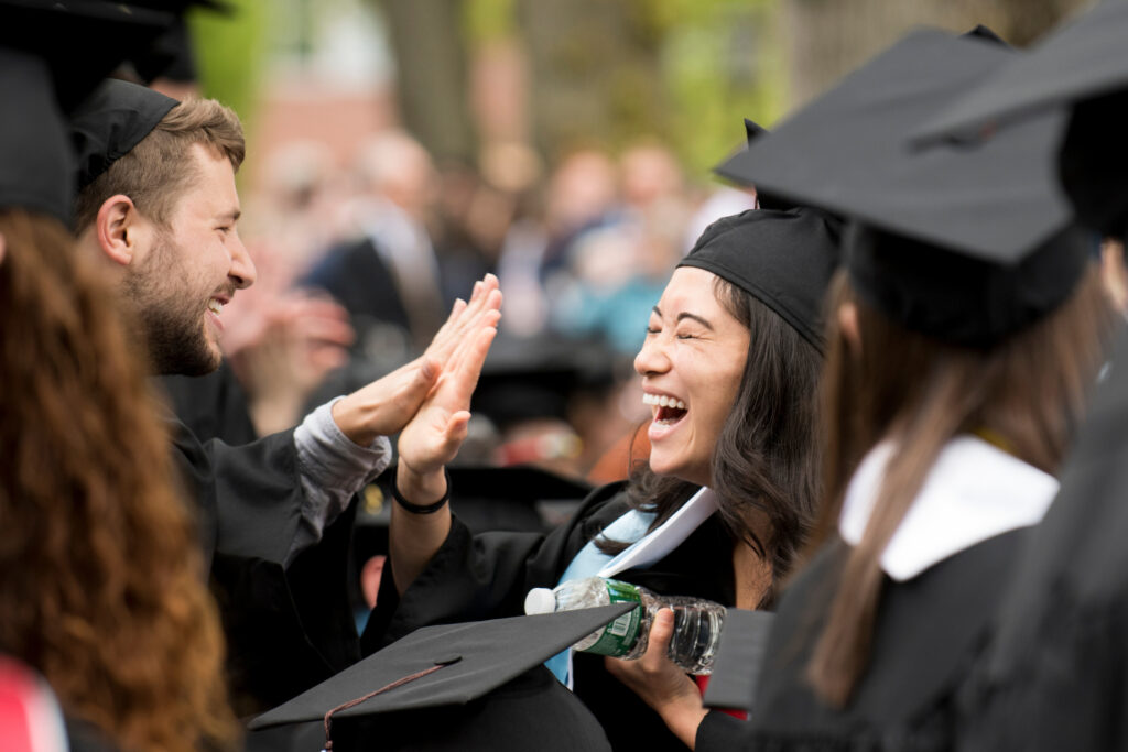 Graduating students high-five each other.