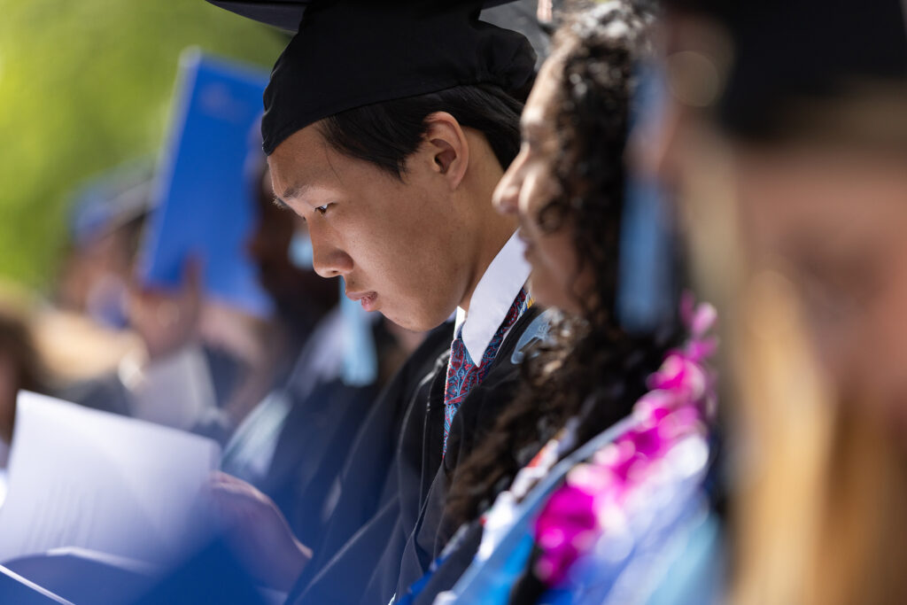 A graduate student looks at the commencement booklet.