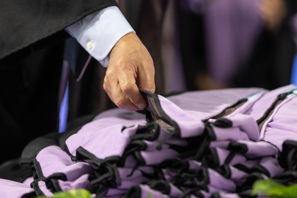 A hand chooses from a selection of Commencement hoods.