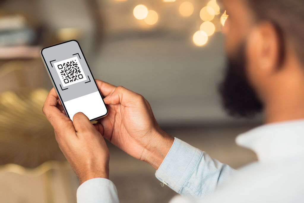A person holds a mobile phone containing a QR code.